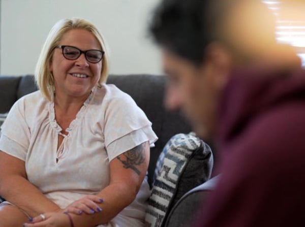 Woman speaking to a group on the couch and smiling