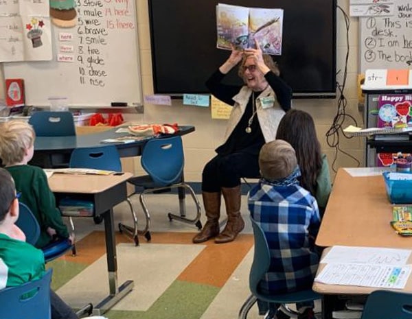A woman reading to students in a classroom